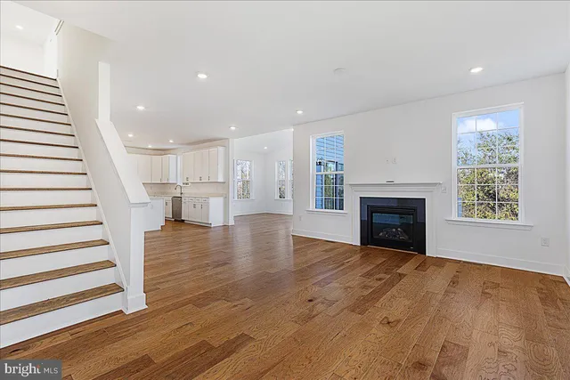 an empty room with wooden floor fireplace and windows