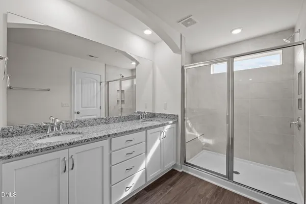 a bathroom with a granite countertop sink a mirror a glass door a shower and vanity