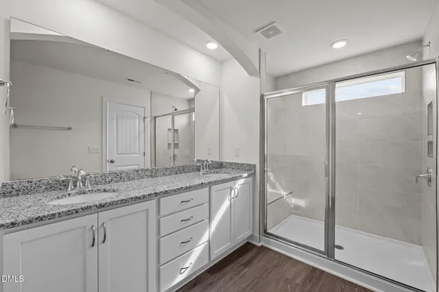 a bathroom with a granite countertop sink a mirror a glass door a shower and vanity