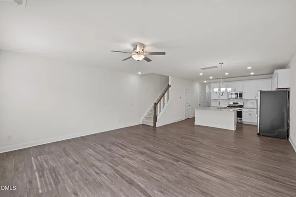 a view of an empty room with wooden floor and a ceiling fan