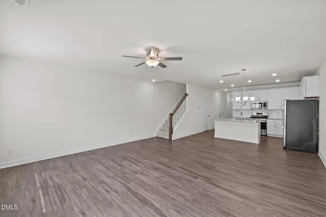 a view of an empty room with wooden floor and a ceiling fan