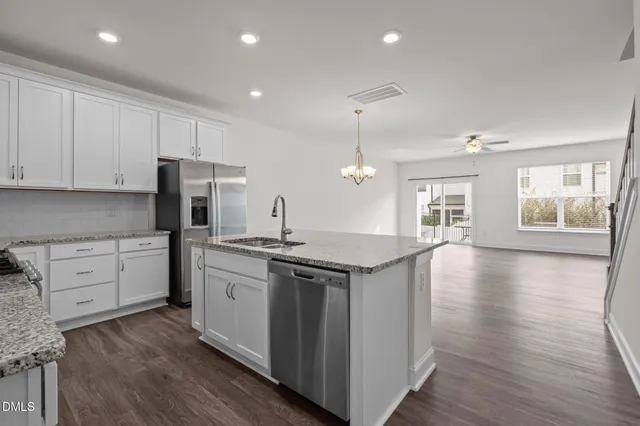 a kitchen with white cabinets stainless steel appliances and wooden floor
