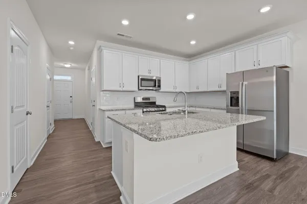 a kitchen with stainless steel appliances granite countertop a refrigerator and a stove top oven