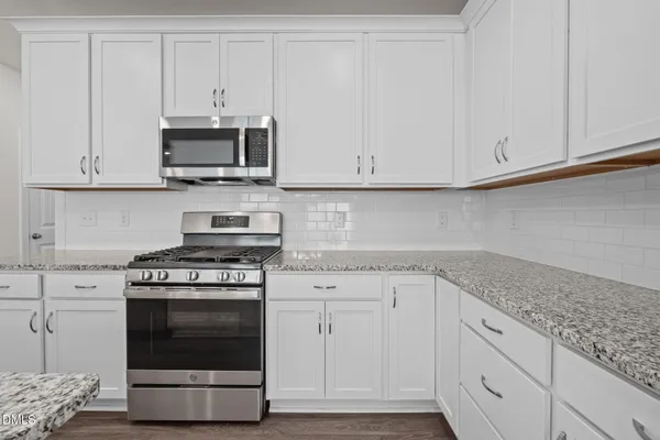 a kitchen with stainless steel appliances granite countertop white cabinets and a stove