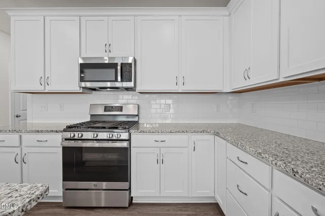 a kitchen with stainless steel appliances granite countertop white cabinets and a stove