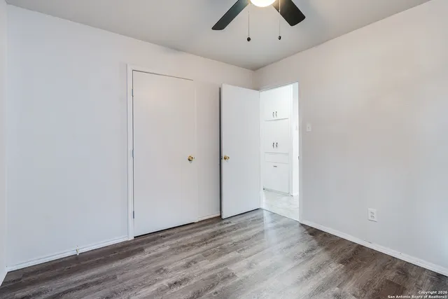 an empty room with wooden floor and a ceiling fan