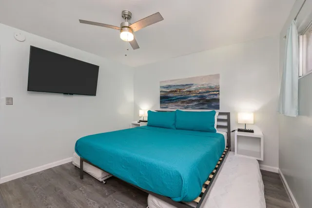 a bedroom with a bed a flat screen tv and a chandelier