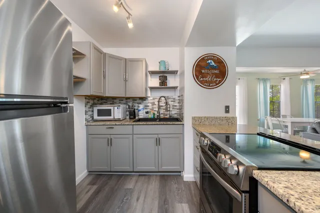 a kitchen with stainless steel appliances granite countertop a sink a stove and a wooden floors