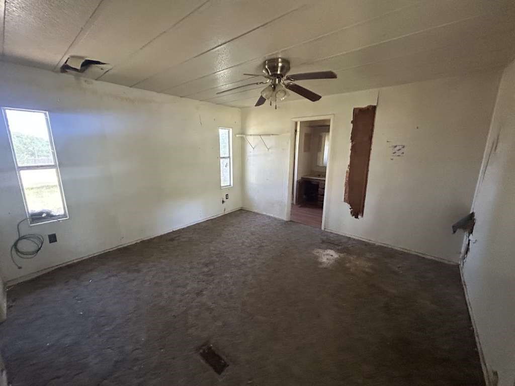 506 Beech Street Jourdanton, TX 78026 - Photo 7 of 11 en empty room with windows and ceiling fan