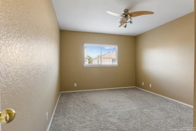 an empty room with a window and a ceiling fan