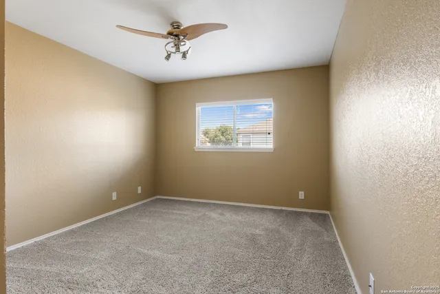an empty room with windows and fan