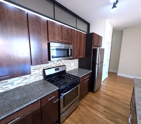 a kitchen with stainless steel appliances granite countertop a refrigerator a stove and a sink