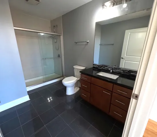 a bathroom with a granite countertop sink toilet and shower