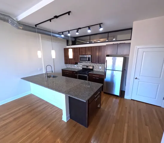 a kitchen with kitchen island wooden floors and stainless steel appliances