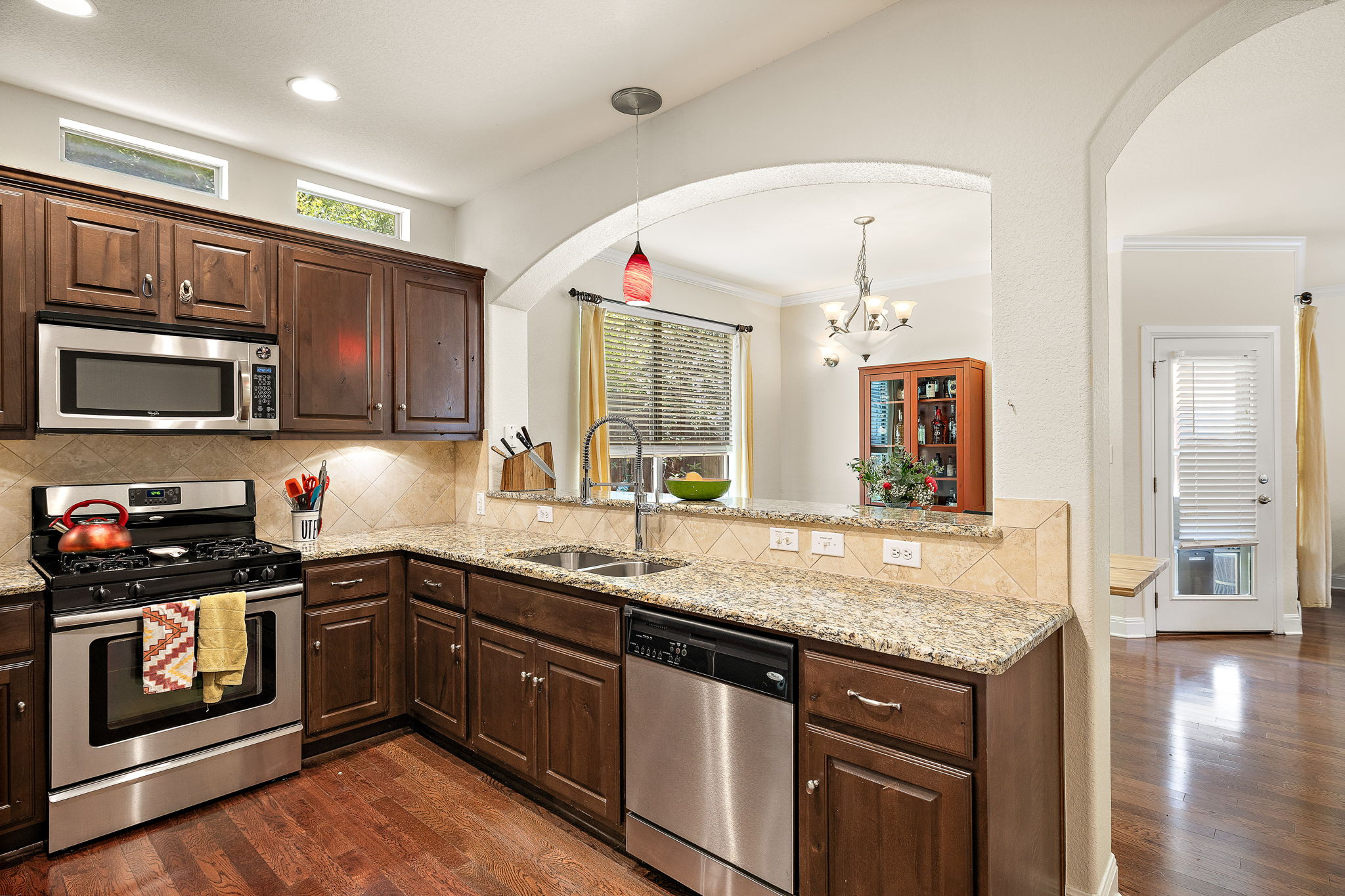 6708 Menchaca Road, Unit 10 Austin, TX 78745 - Photo 9 of 28 Kitchen featuring wood-finish flooring, dark wood cabinetry, granite countertops, and stainless steel appliances