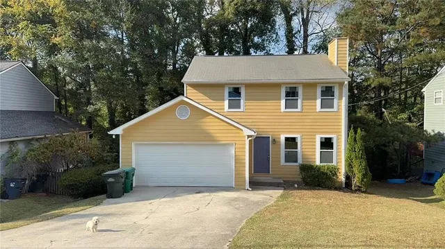 a view of a white house with a large tree next to a yard