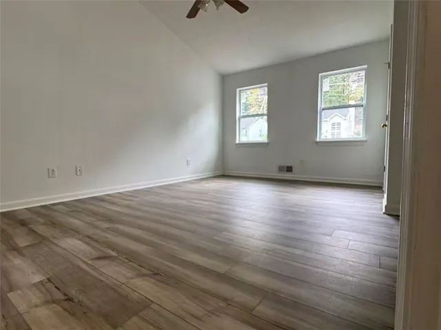 a view of an empty room with wooden floor and a window
