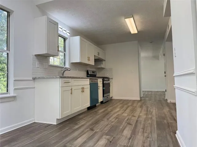 a kitchen with a white cabinets and wooden floor