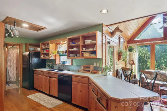 a kitchen with stainless steel appliances granite countertop a refrigerator a sink dishwasher a stove and a dining table with wooden floor