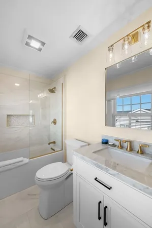 a bathroom with a granite countertop sink a toilet a mirror and shower