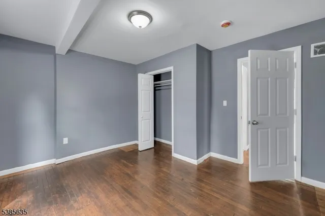 an empty room with wooden floor and closet