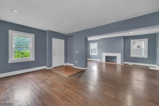 a view of empty room with wooden floor and fireplace