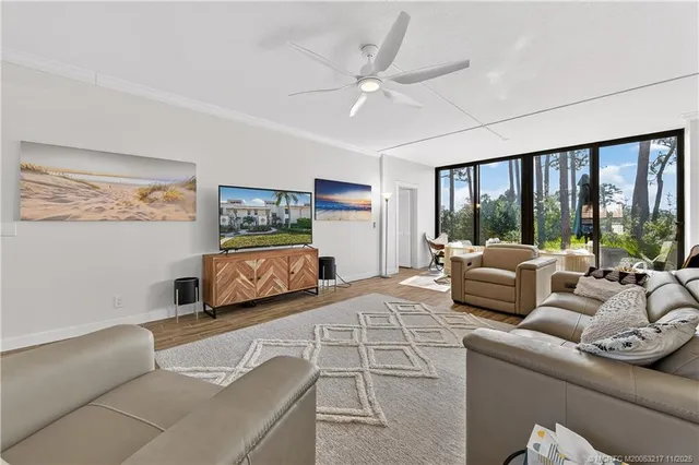 a living room with furniture large window and a ceiling fan