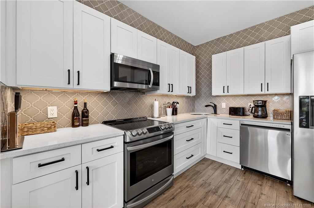 13438 Northwest Harbour Ridge Boulevard, Unit 3A Palm City, FL 34990 - Photo 10 of 19 a kitchen with stainless steel appliances granite countertop a stove a sink dishwasher and a microwave oven with wooden cabinets