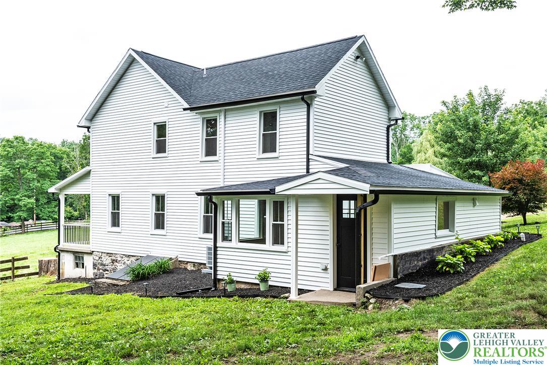72 Allegheny Road Mount Bethel, PA 18343 - Photo 47 of 72 A classic white home with a dark roof and fresh landscaping sits on a verdant hillside.