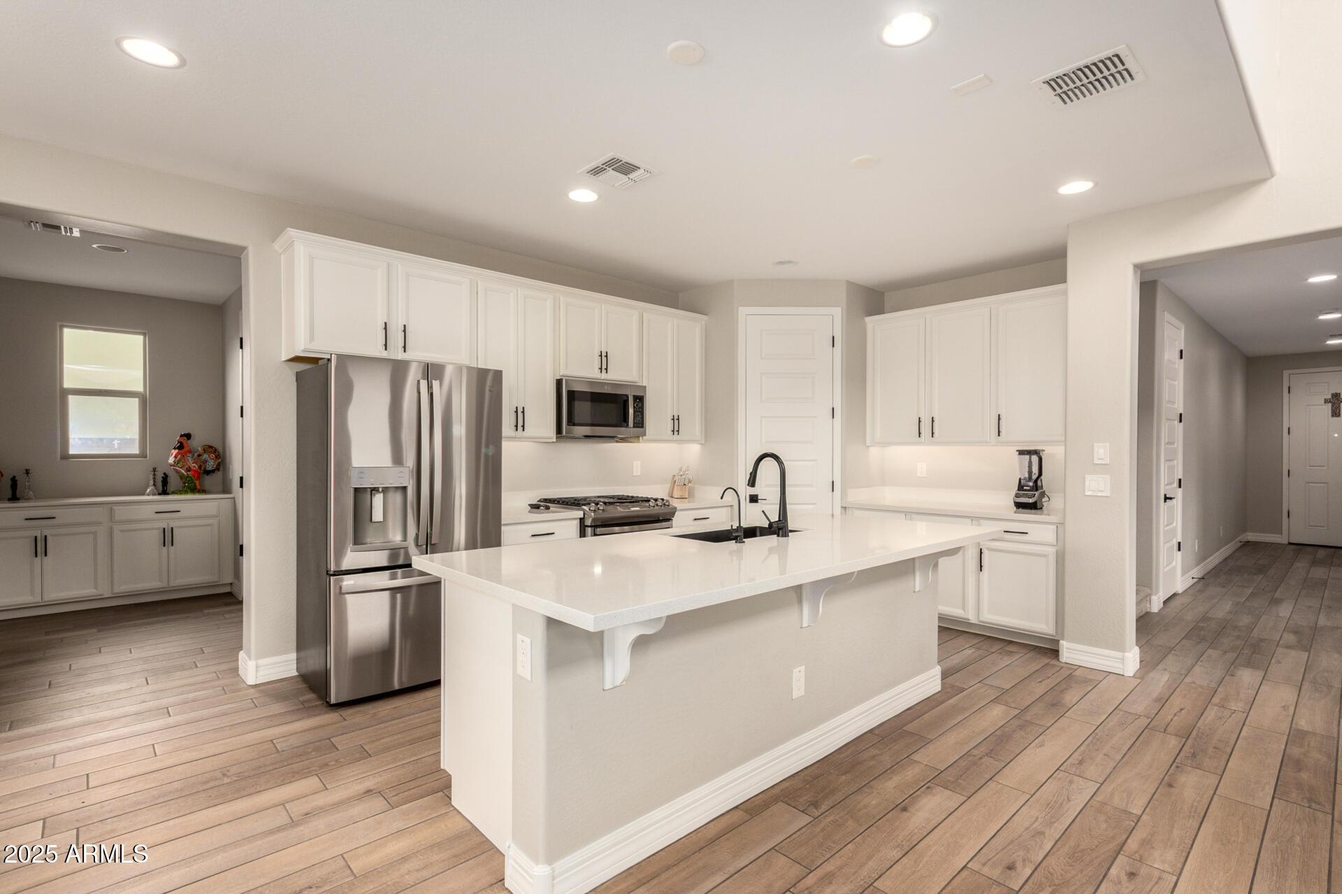 5126 West Roundhouse Road Laveen, AZ 85339 - Photo 16 of 39 a kitchen with stainless steel appliances a refrigerator a sink dishwasher a stove top oven a refrigerator and white cabinets with wooden floor