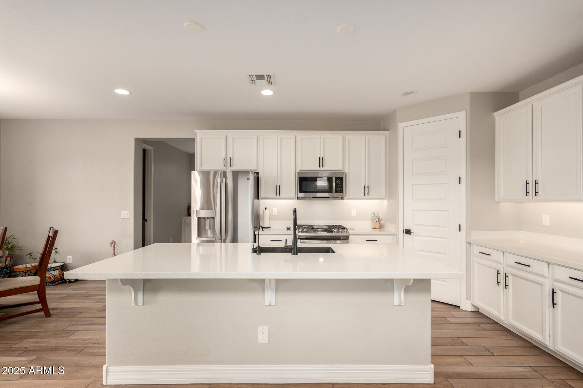 5126 West Roundhouse Road Laveen, AZ 85339 - Photo 18 of 39 a kitchen with stainless steel appliances kitchen island granite countertop a refrigerator a stove a sink and white cabinets with wooden floor