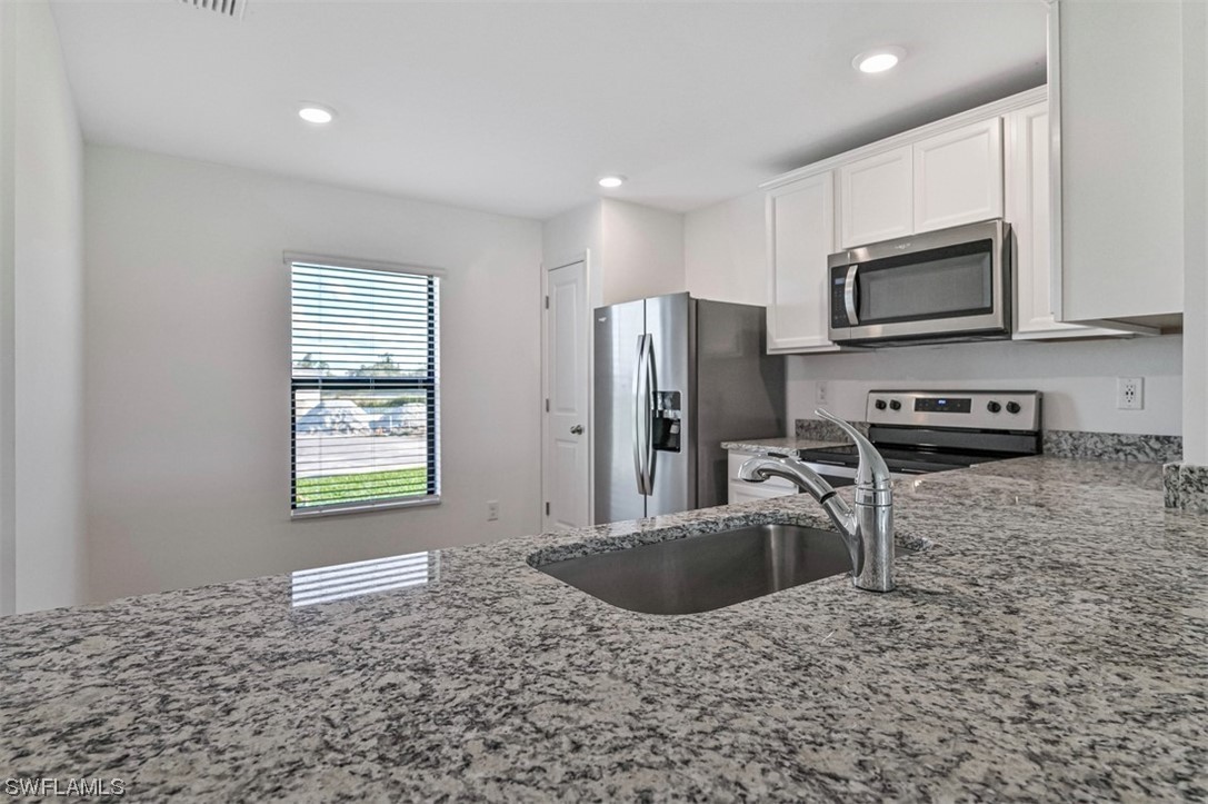 880 General Chesty Puller Court LaBelle, FL 33935 - Photo 7 of 21 a kitchen with stainless steel appliances granite countertop a sink a stove a microwave a refrigerator and a stove