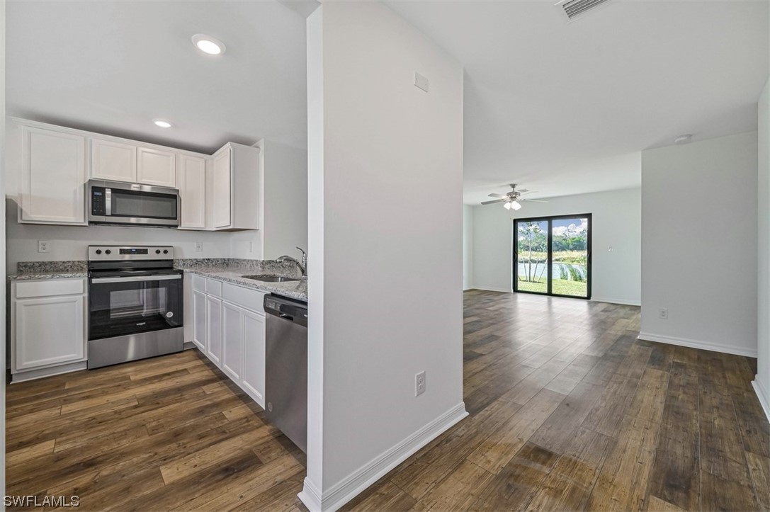880 General Chesty Puller Court LaBelle, FL 33935 - Photo 8 of 21 a kitchen with stainless steel appliances a stove top oven a sink dishwasher a refrigerator and a microwave oven with wooden floor