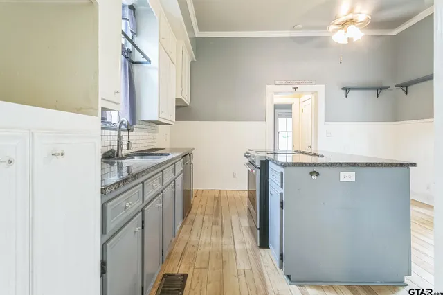 a kitchen with granite countertop a stove cabinets and wooden floor