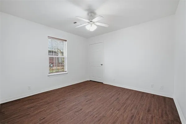an empty room with wooden floor chandelier fan and windows