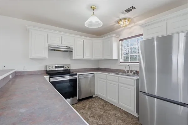 a kitchen with cabinets appliances a sink and a window
