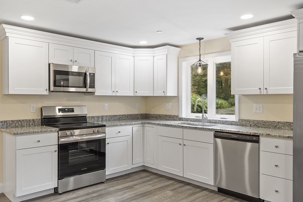 a kitchen with granite countertop white cabinets white stainless steel appliances and a sink
