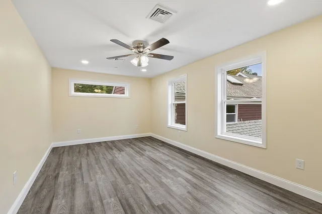 a view of an empty room with a window and wooden floor