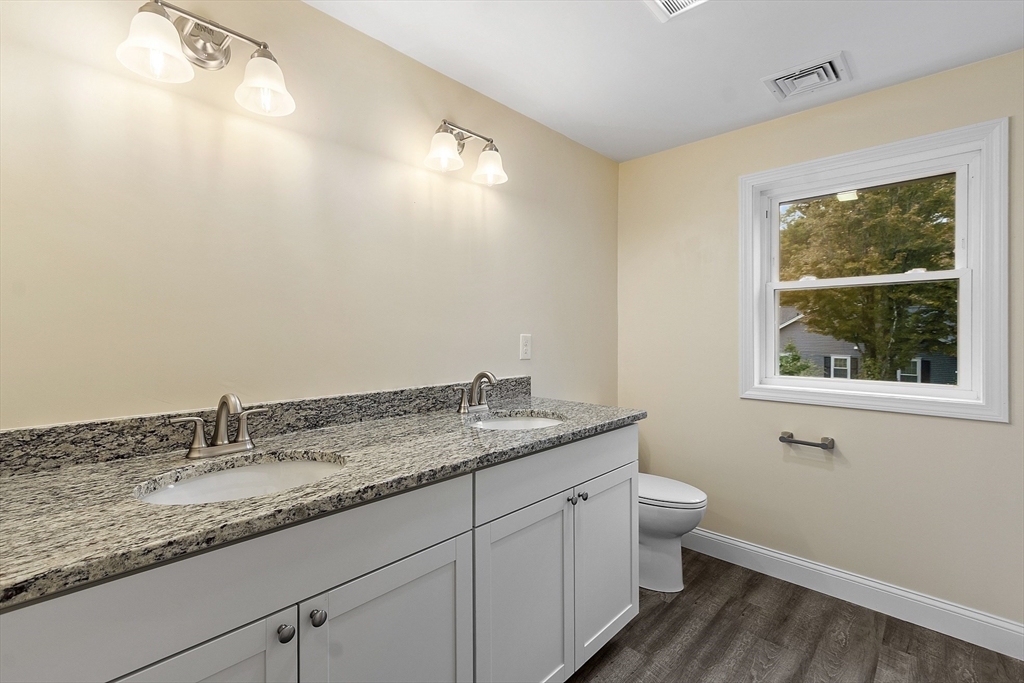 20 Townsend Street, Unit 1 Pepperell, MA 01463 - Photo 12 of 25 a bathroom with a granite countertop sink a toilet and with mirror