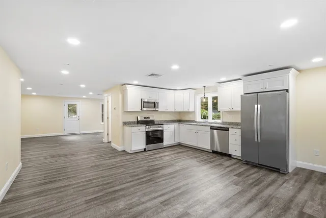a large kitchen with a center island wooden floor and stainless steel appliances