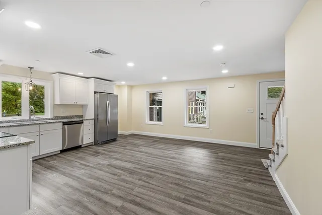 a view of kitchen with stainless steel appliances wooden floor and cabinets