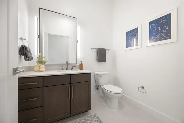 a bathroom with a toilet a sink a mirror a window and vanity