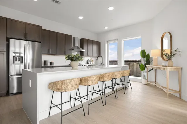 a kitchen with stainless steel appliances a dining table chairs and refrigerator