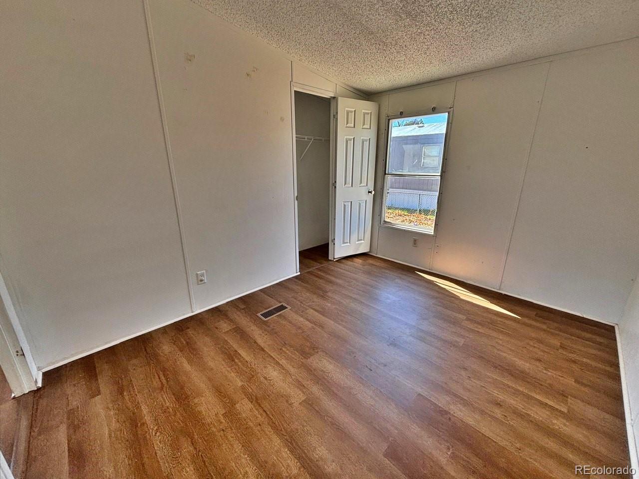 1205 Reed Lane La Junta, CO 81050 - Photo 19 of 26 a view of an empty room with wooden floor and a window