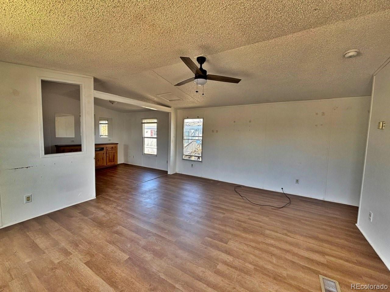 1205 Reed Lane La Junta, CO 81050 - Photo 3 of 26 an empty room with wooden floor and ceiling fan