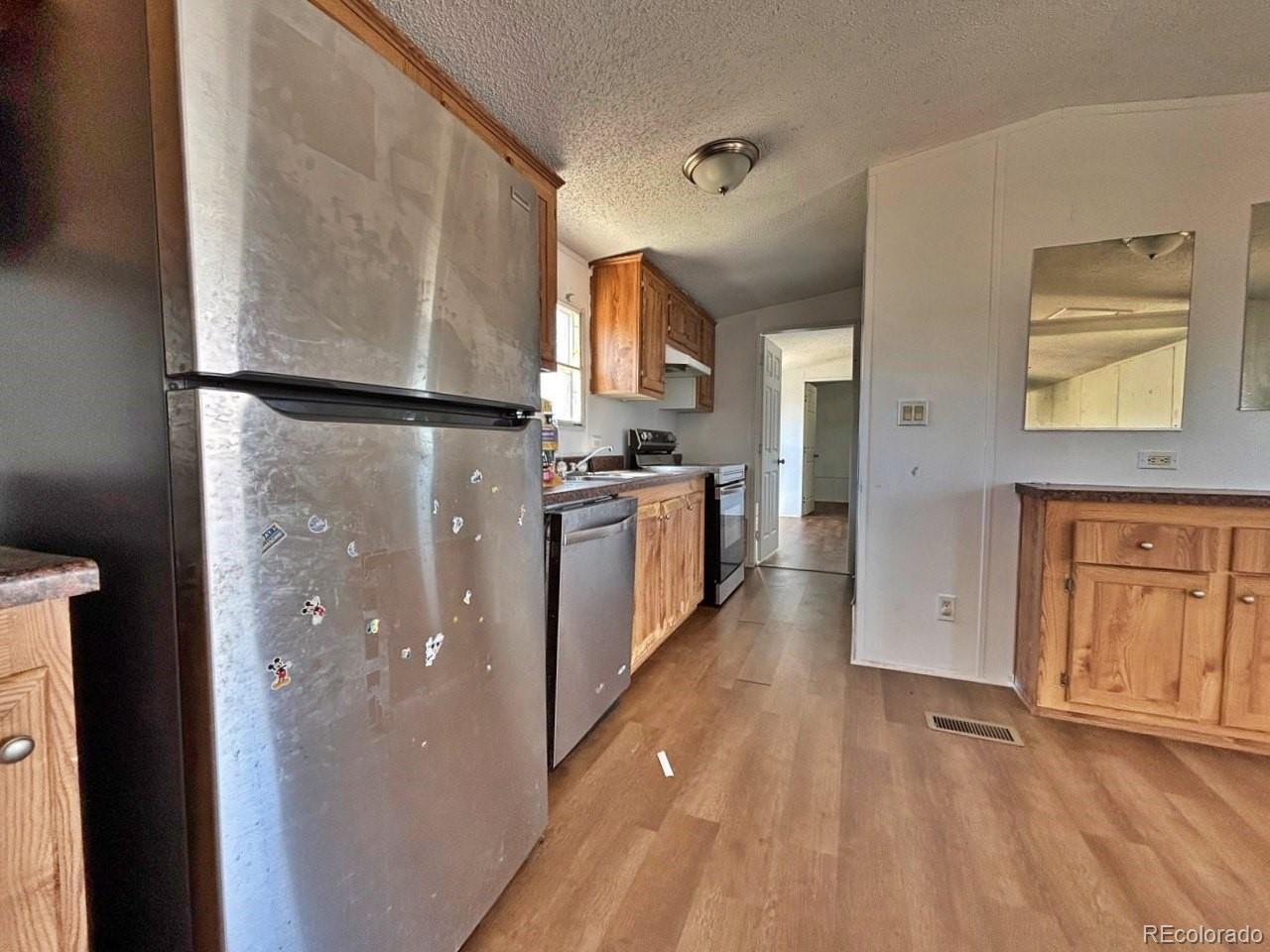 1205 Reed Lane La Junta, CO 81050 - Photo 7 of 26 a kitchen with stainless steel appliances granite countertop a refrigerator a stove and a sink with wooden floors