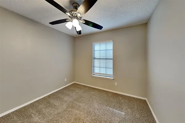 an empty room with windows and ceiling fan
