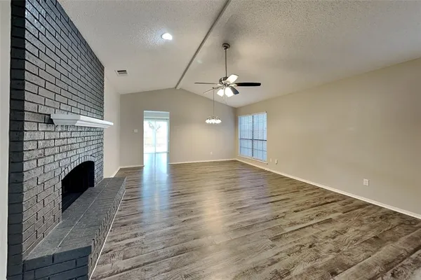 a view of an empty room with wooden floor and a fireplace