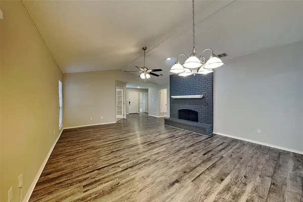 a view of a livingroom with a fireplace a chandelier and wooden floor