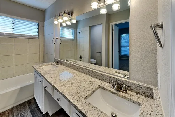 a bathroom with a granite countertop double vanity sink and a mirror